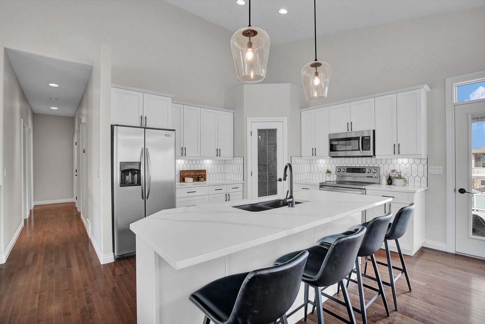 White kitchen with quartz island and pendant lighting, from the Aimee Lauren Interiors kitchen and bath portfolio