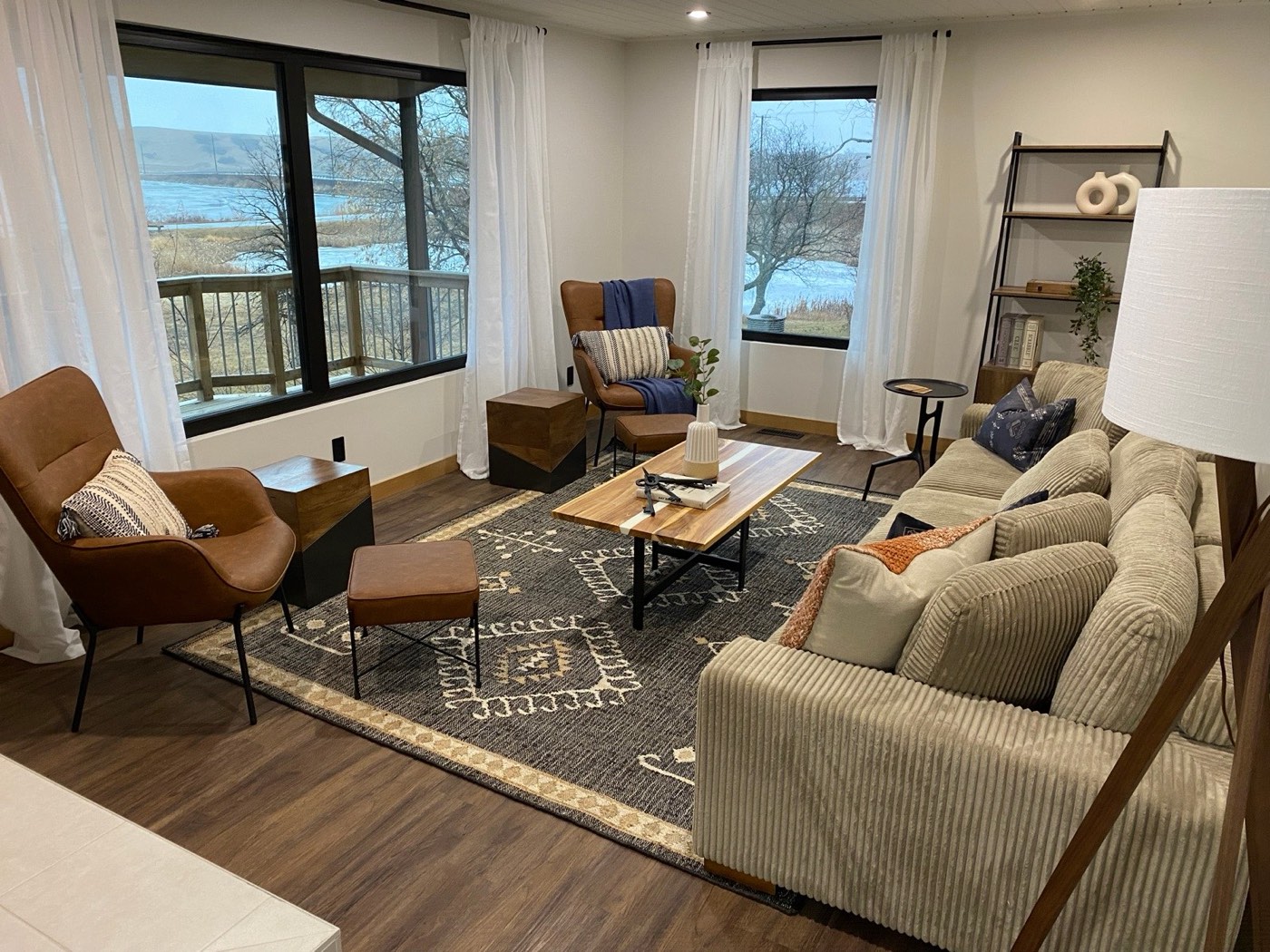 Staged living room with lake views, layered rugs, and leather chairs by Aimee Lauren Interiors